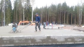 Työntekijä tasoittaa talon betonipohjaa